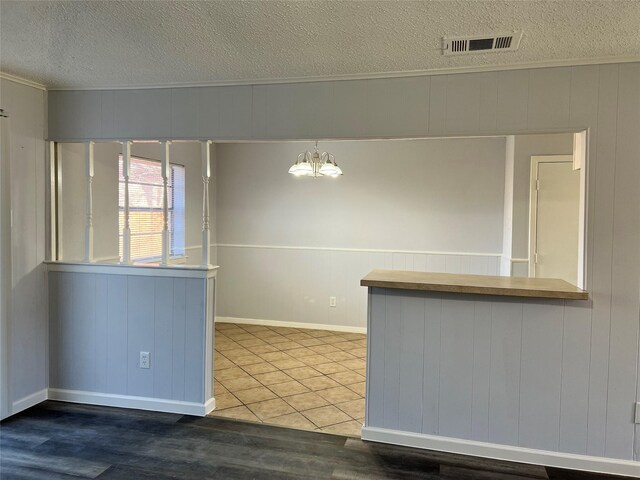 interior space featuring tile patterned flooring, a notable chandelier, kitchen peninsula, a textured ceiling, and decorative light fixtures