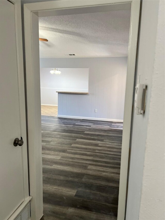 hallway featuring a textured ceiling and dark hardwood / wood-style floors