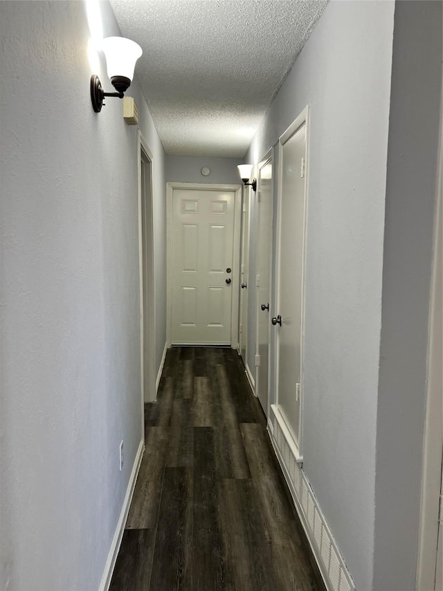 hall with a textured ceiling and dark hardwood / wood-style flooring