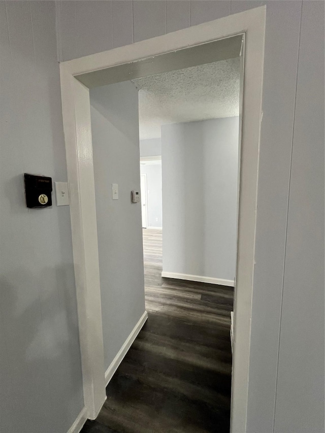 corridor with dark wood-type flooring and a textured ceiling