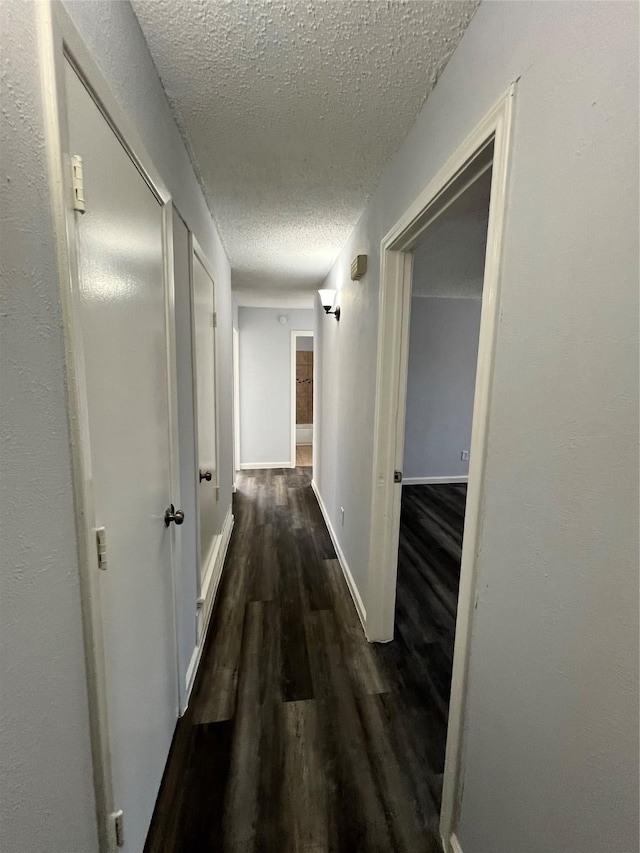 hallway featuring a textured ceiling and dark hardwood / wood-style floors