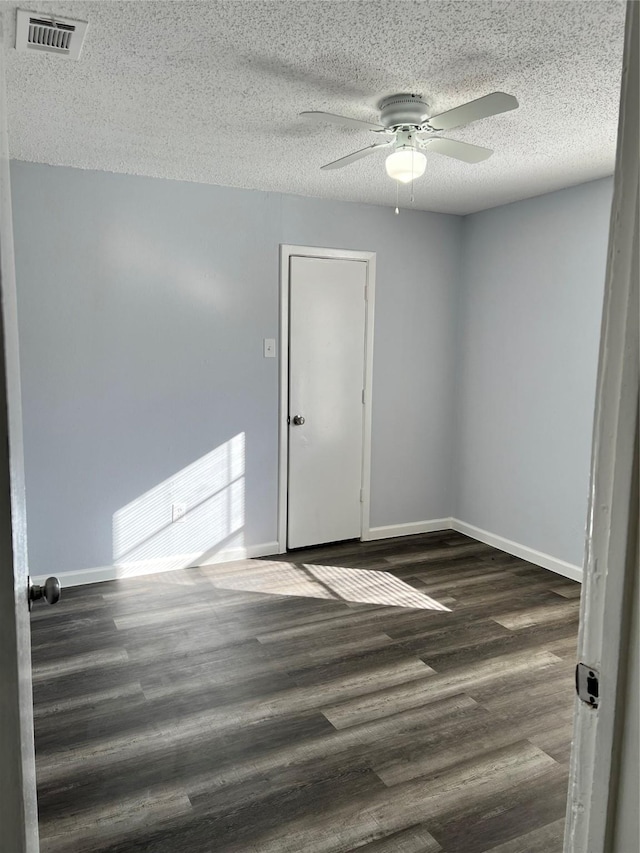 empty room with a textured ceiling, dark hardwood / wood-style floors, and ceiling fan