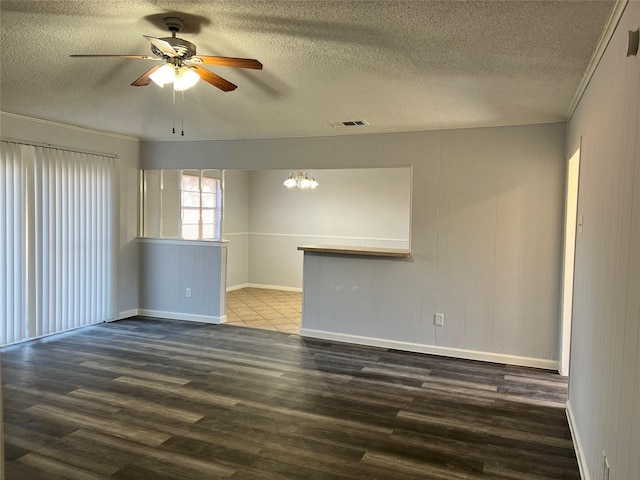 empty room with ceiling fan with notable chandelier, dark hardwood / wood-style flooring, and crown molding