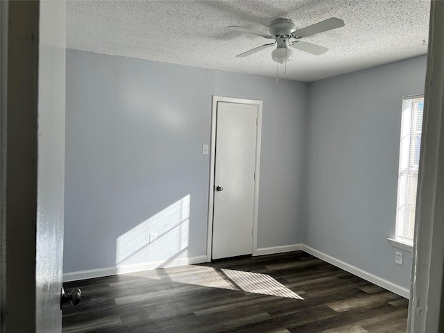 spare room featuring ceiling fan, dark hardwood / wood-style flooring, a healthy amount of sunlight, and a textured ceiling