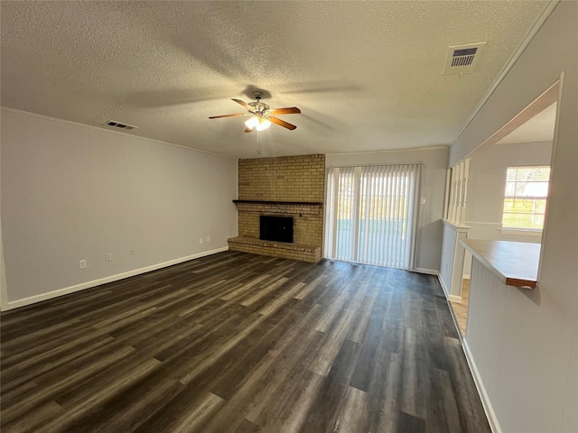 unfurnished living room featuring dark wood-type flooring, a brick fireplace, ceiling fan, and a healthy amount of sunlight