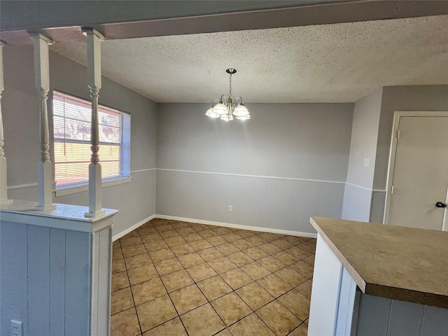 unfurnished dining area with light tile patterned floors, a textured ceiling, and an inviting chandelier