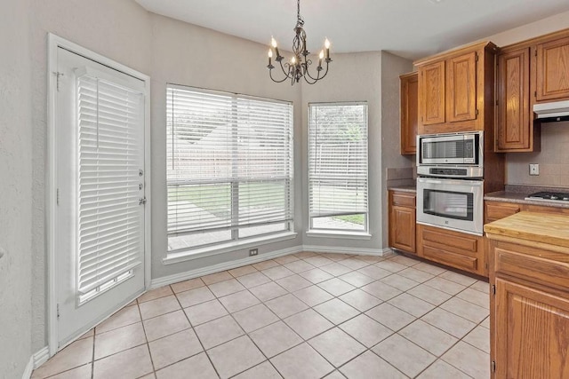 5400 Belle Chasse Ln, Frisco, TX 75035 - kitchen with appliances with stainless steel finishes, a chandelier, light countertops, light tile patterned floors, and under cabinet range hood