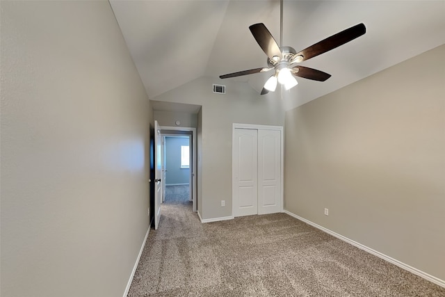 unfurnished bedroom featuring ceiling fan, a closet, light colored carpet, and lofted ceiling