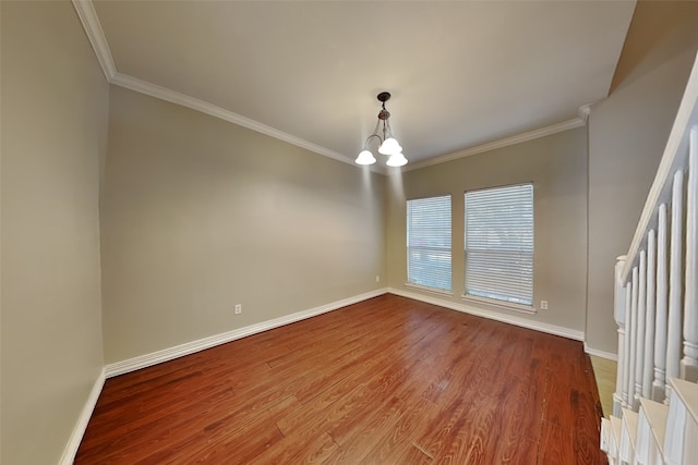 spare room featuring hardwood / wood-style flooring, crown molding, and a notable chandelier