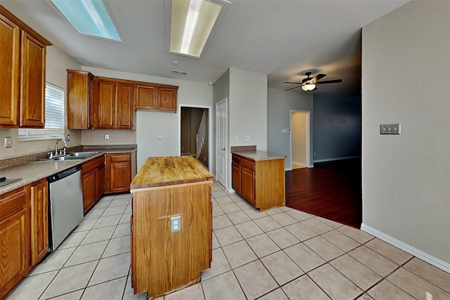 kitchen featuring ceiling fan, a center island, wood counters, stainless steel dishwasher, and light tile patterned floors