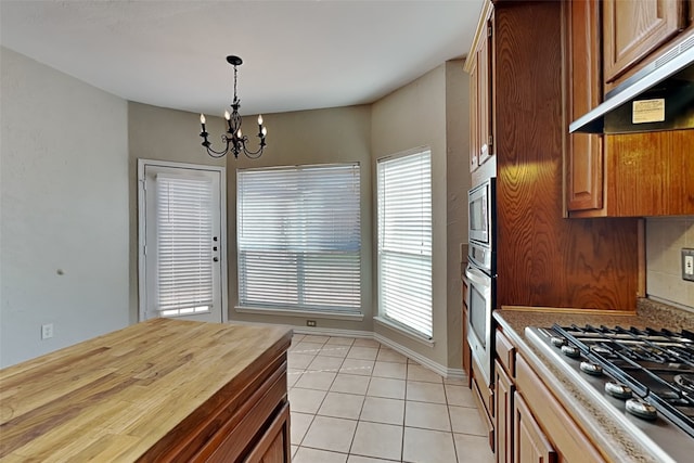 kitchen featuring stainless steel appliances, exhaust hood, a chandelier, hanging light fixtures, and butcher block counters