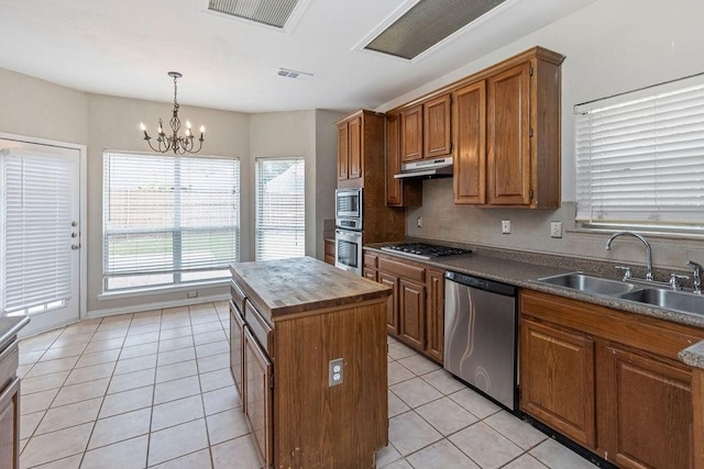 5400 Belle Chasse Ln, Frisco, TX 75035 - kitchen with stainless steel appliances, a sink, under cabinet range hood, wooden counters, and a chandelier