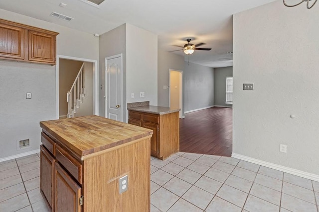 5400 Belle Chasse Ln, Frisco, TX 75035 - kitchen with light tile patterned floors, ceiling fan, wood counters, baseboards, and brown cabinetry