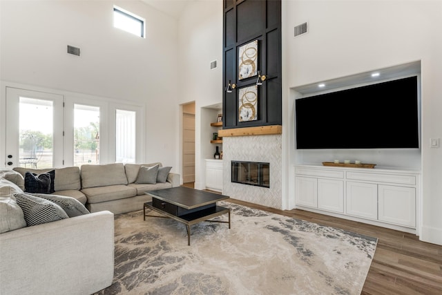 living room with wood-type flooring, a fireplace, and a high ceiling