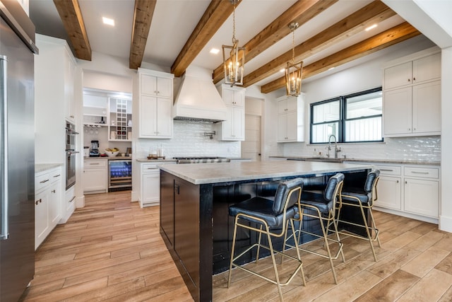 kitchen featuring white cabinets, custom exhaust hood, a kitchen island, and sink