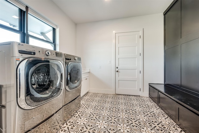 clothes washing area with cabinets, light tile patterned floors, and washing machine and dryer