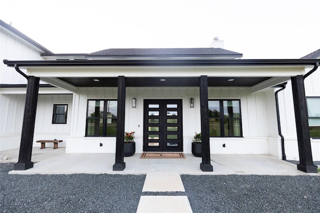 property entrance featuring covered porch, a shingled roof, and board and batten siding