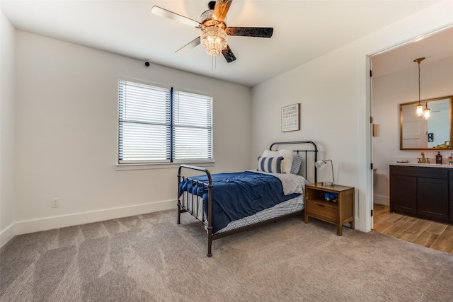 bedroom with ceiling fan, sink, light carpet, and ensuite bath