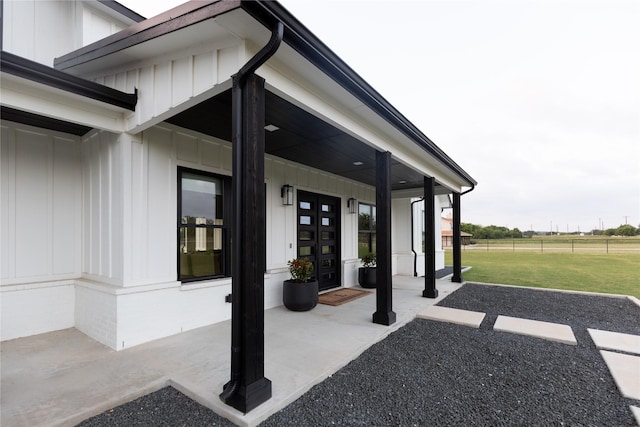 doorway to property with board and batten siding and a lawn