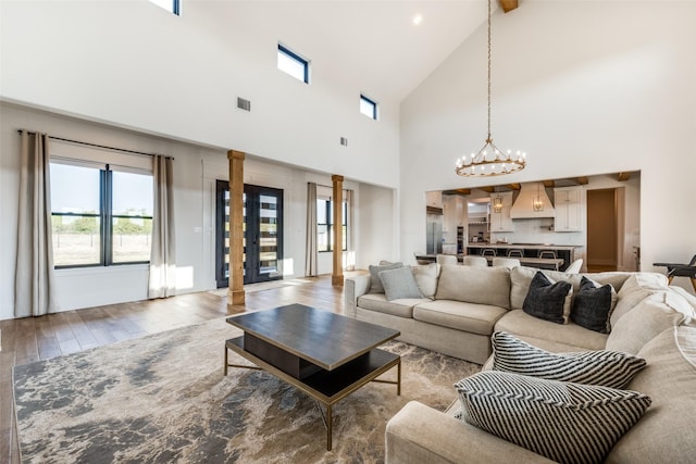 living room featuring a towering ceiling, a chandelier, and light wood-type flooring