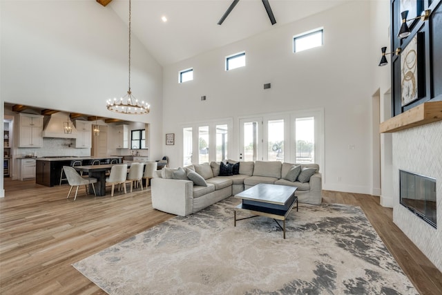 living room with a tiled fireplace, a chandelier, a towering ceiling, and a healthy amount of sunlight