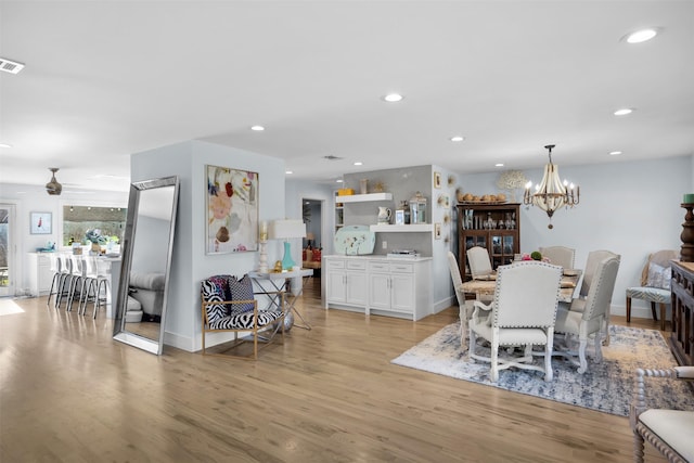 dining room featuring ceiling fan with notable chandelier and light hardwood / wood-style flooring