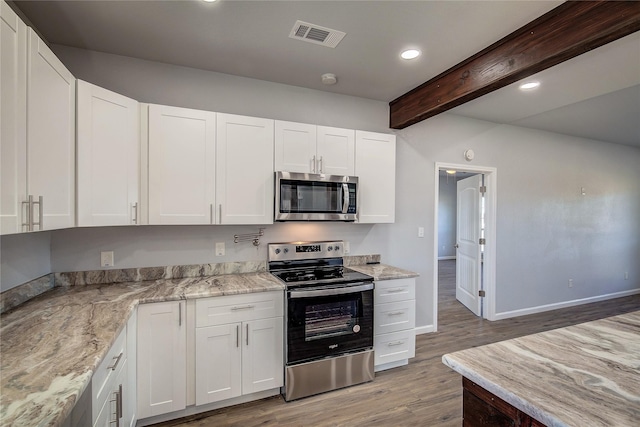 kitchen with white cabinets, light wood-type flooring, beamed ceiling, light stone counters, and stainless steel appliances