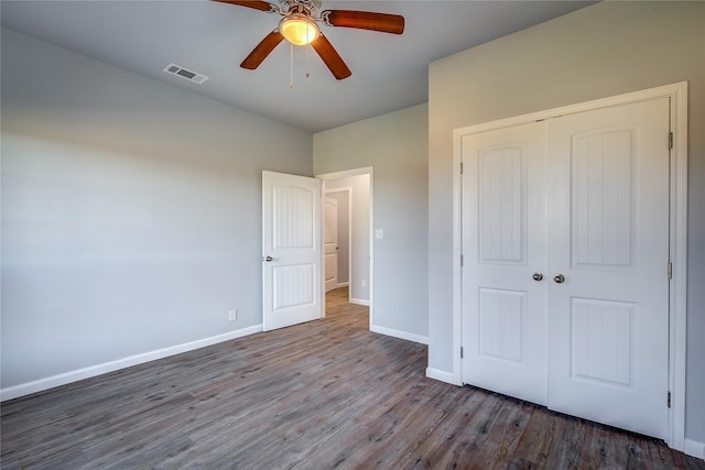 unfurnished bedroom with dark hardwood / wood-style flooring, a closet, and ceiling fan