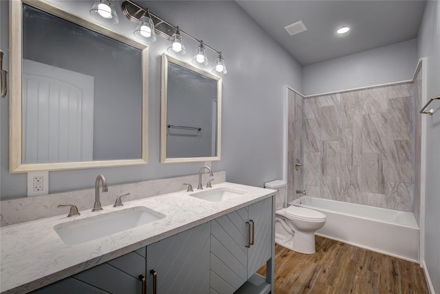 full bathroom featuring hardwood / wood-style floors, vanity, toilet, and tiled shower / bath