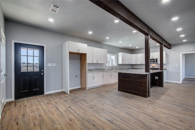 kitchen with beamed ceiling, a kitchen breakfast bar, white cabinetry, and a kitchen island