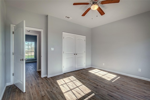 unfurnished bedroom with a closet, dark wood-type flooring, and ceiling fan