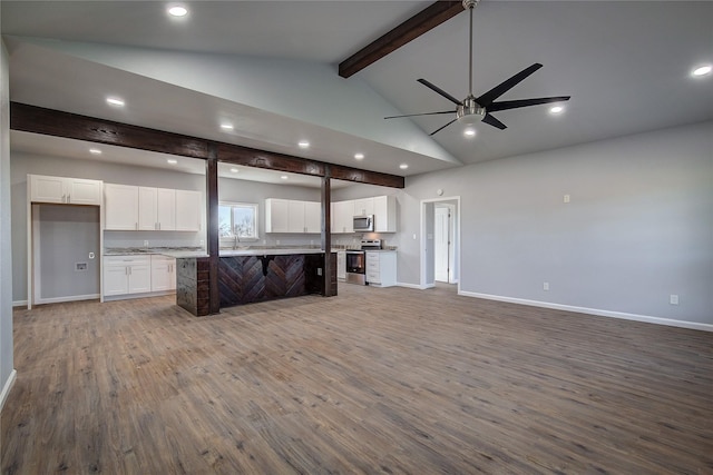 interior space featuring a center island, ceiling fan, beamed ceiling, white cabinetry, and stainless steel appliances