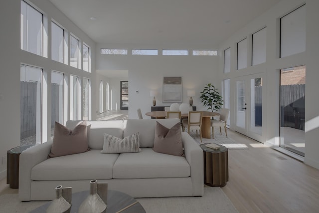 living room featuring plenty of natural light, light hardwood / wood-style floors, a high ceiling, and french doors