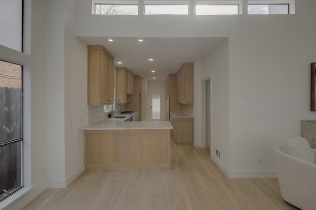 kitchen with light hardwood / wood-style floors, light brown cabinets, and kitchen peninsula