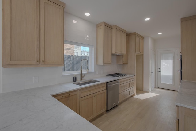 kitchen with light wood-type flooring, light stone counters, stainless steel appliances, sink, and light brown cabinets