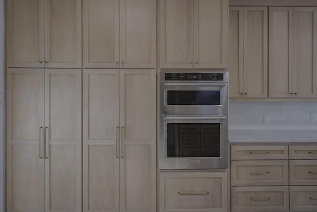 kitchen featuring decorative backsplash, light brown cabinetry, and double oven