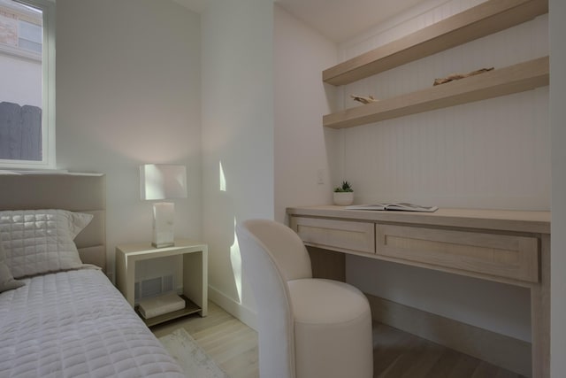 bedroom with light wood-type flooring and built in desk