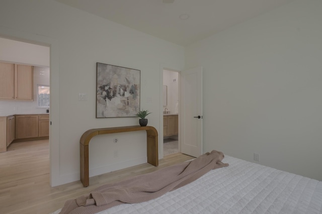 bedroom with ensuite bath and light hardwood / wood-style flooring