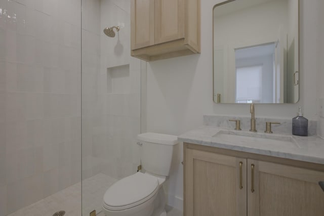 bathroom with vanity, toilet, and a tile shower