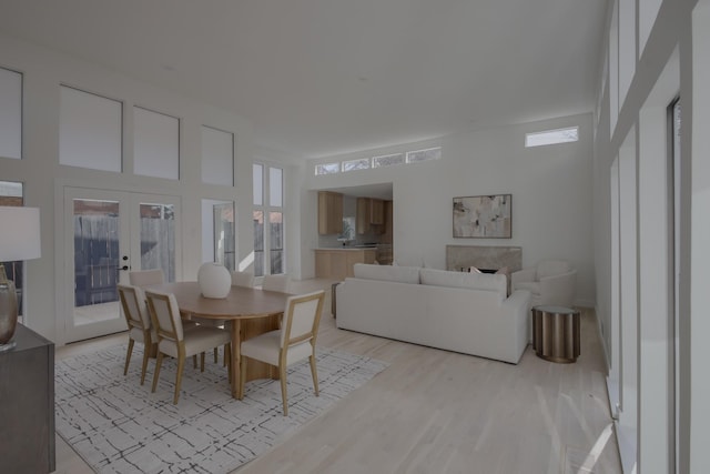 dining area featuring light hardwood / wood-style floors, a towering ceiling, and french doors