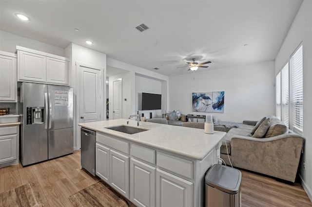 kitchen with white cabinets, appliances with stainless steel finishes, a kitchen island with sink, and sink