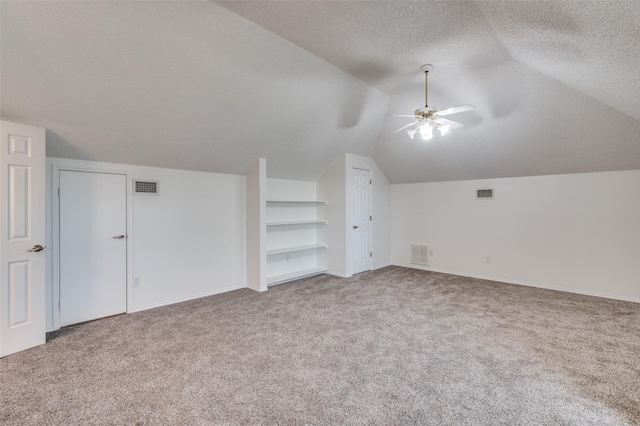 additional living space with carpet, built in shelves, a textured ceiling, ceiling fan, and lofted ceiling