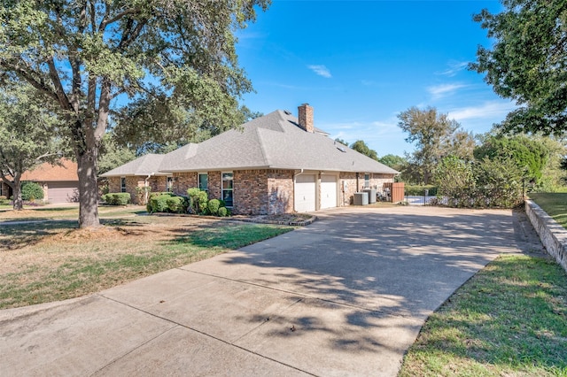 view of side of property with a garage, a yard, and central AC