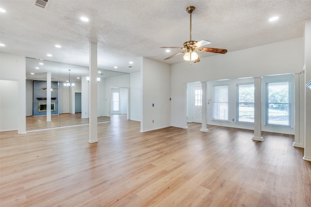 unfurnished living room featuring a fireplace, a textured ceiling, light hardwood / wood-style floors, and ceiling fan