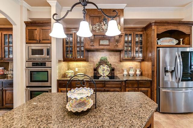 kitchen featuring light stone counters, ornamental molding, stainless steel appliances, and tasteful backsplash