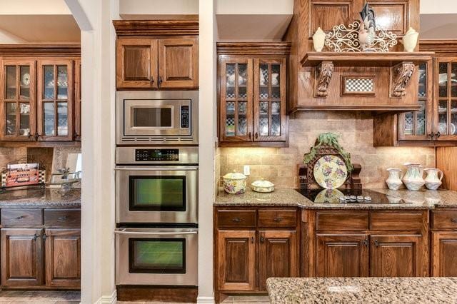 kitchen featuring tasteful backsplash, light stone countertops, and stainless steel appliances