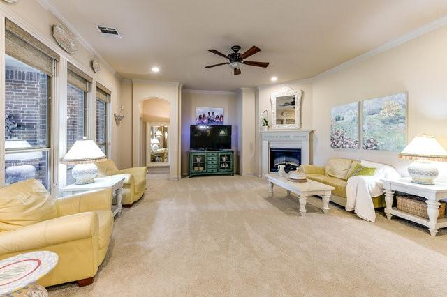 carpeted living room with crown molding and ceiling fan