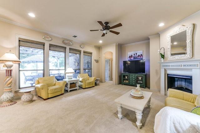 carpeted living room featuring ornamental molding and ceiling fan