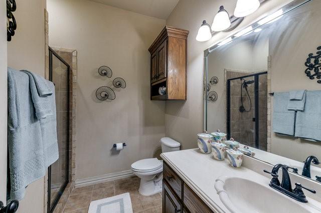 bathroom with tile patterned flooring, vanity, toilet, and walk in shower