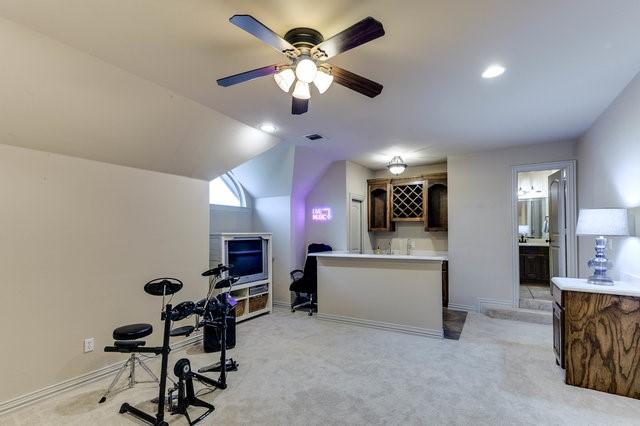 workout room with ceiling fan, lofted ceiling, bar, and light carpet